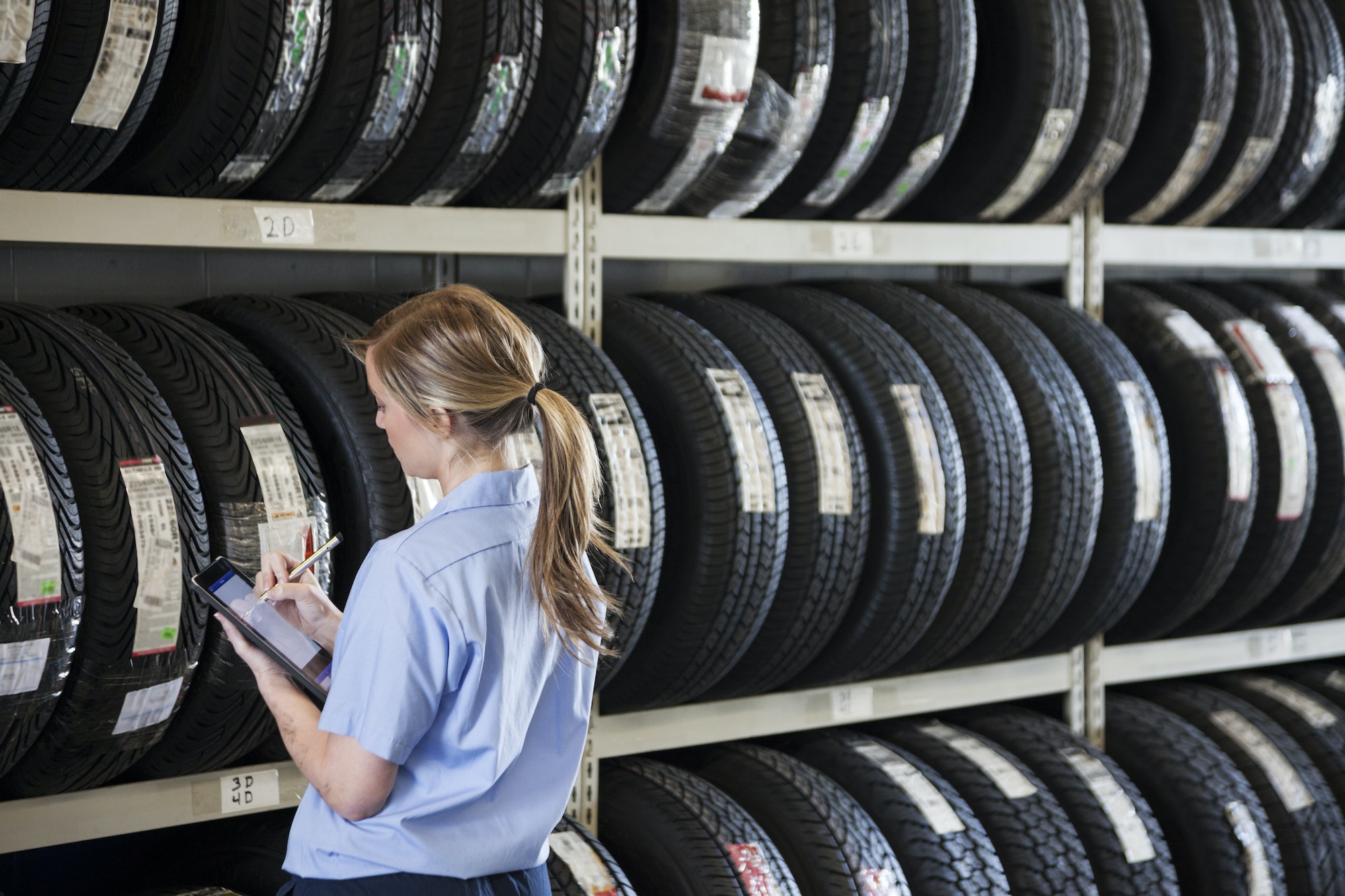 Young female mechanic takes inventory of new tires in repair shop